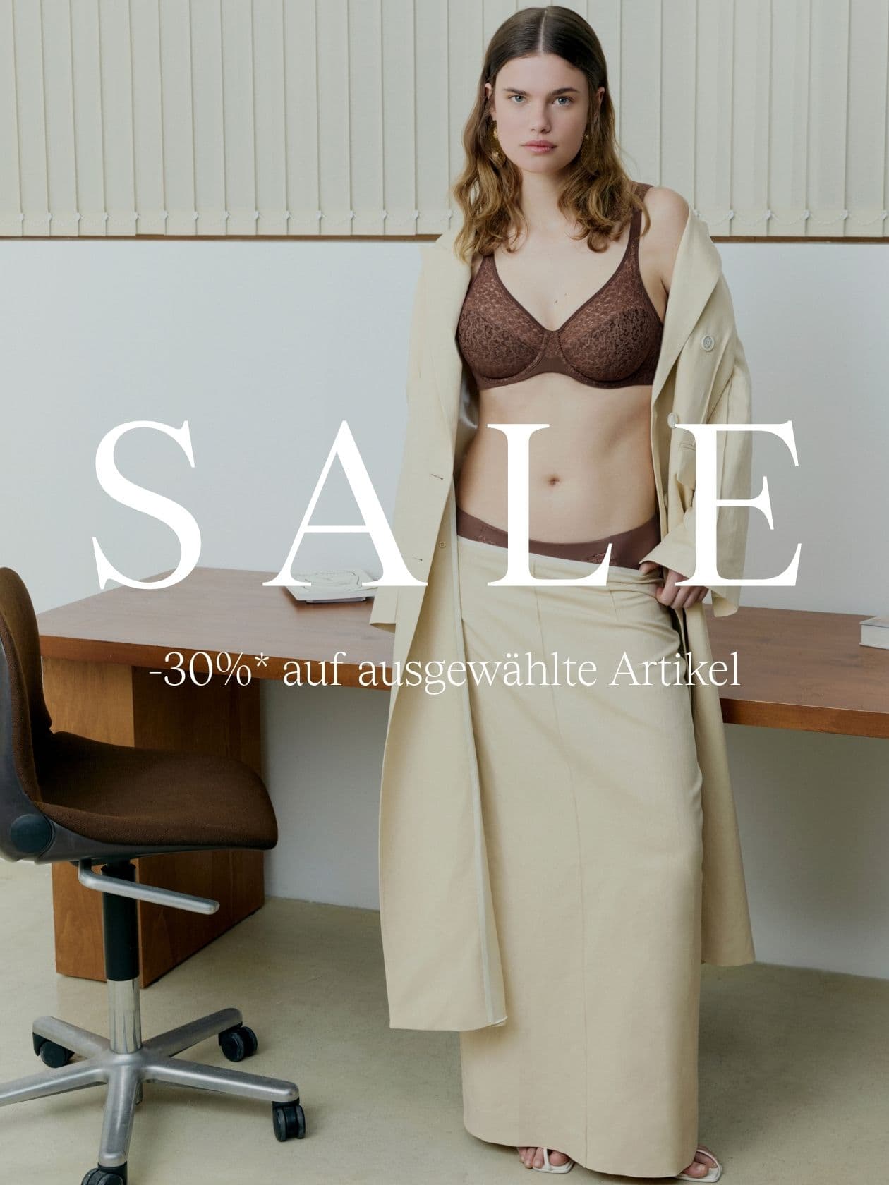 Woman in brown lingerie and beige coat in an office setting. Text reads "SALE" and "-30%* auf ausgewählte Artikel."