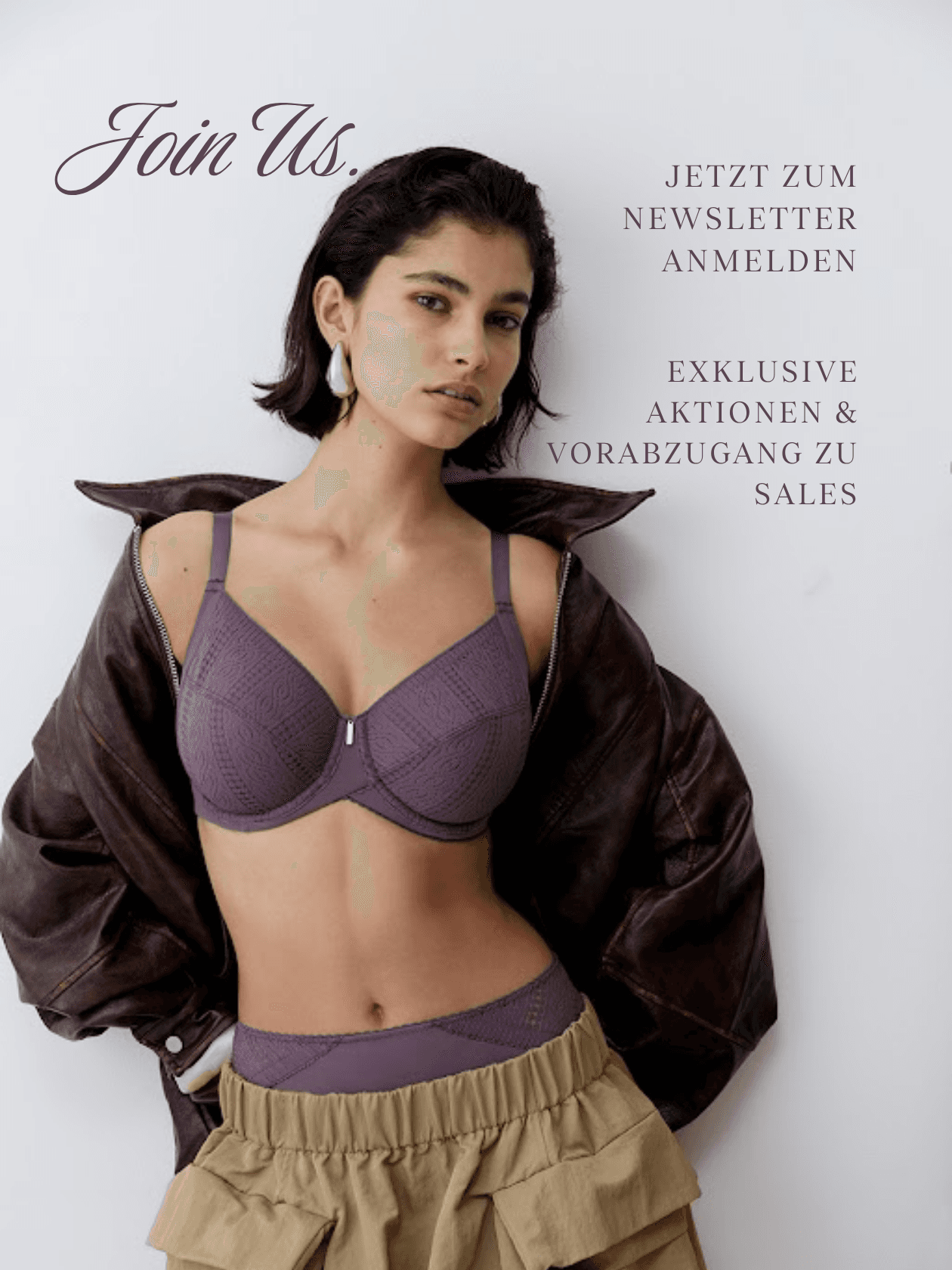 Woman in a purple bra and brown jacket, wearing a beige ruffled skirt. Text reads, "Join Us" and "Jetzt zum Newsletter anmelden."
