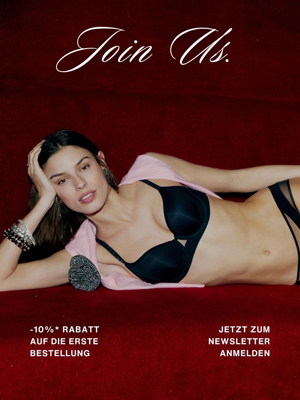 Person in a black bra with jewelry, reclining on a red surface. Text promotes a 10% discount and newsletter sign-up in German.