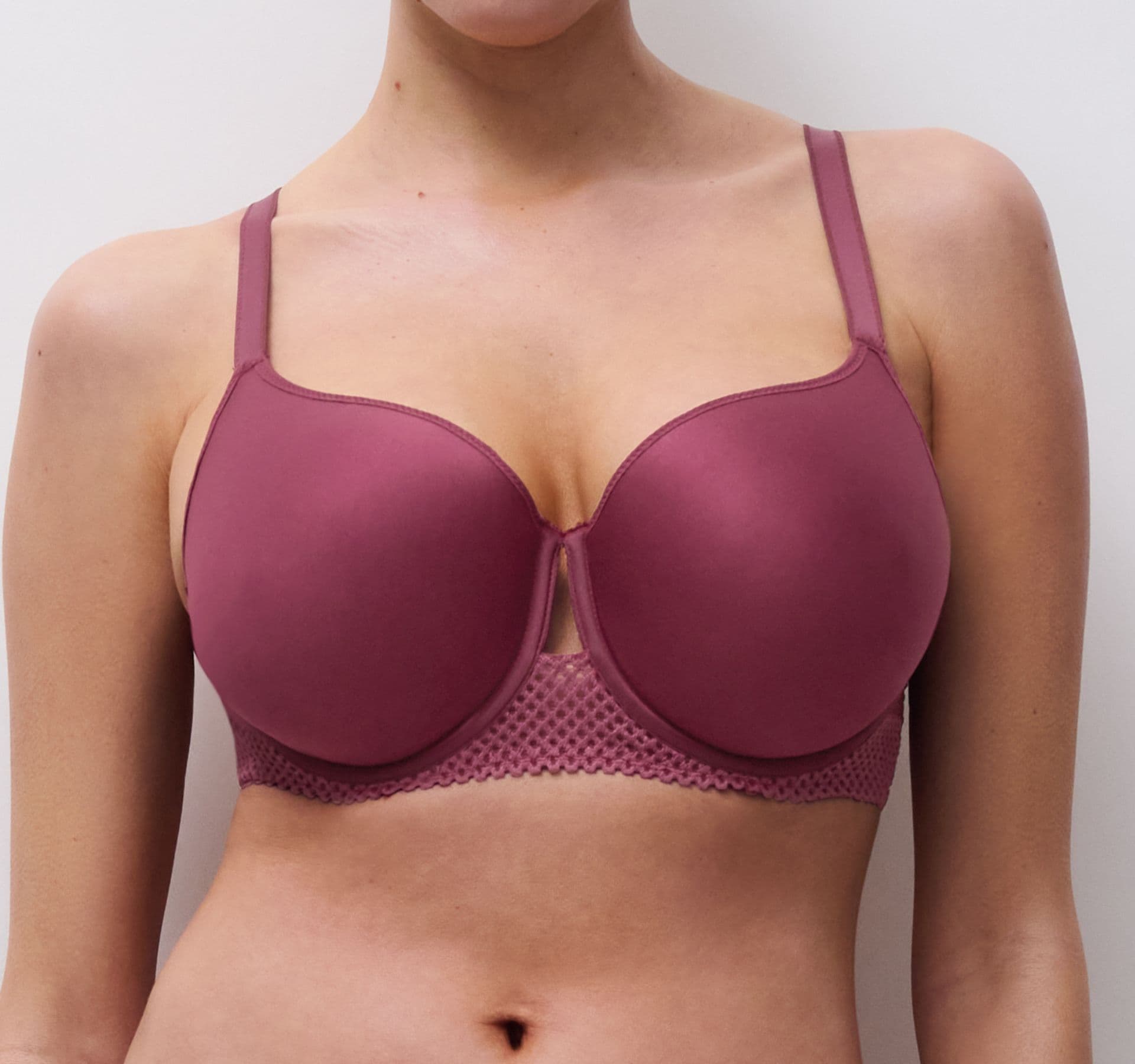 Person wearing a mauve bra with lace detailing, standing against a plain white background.