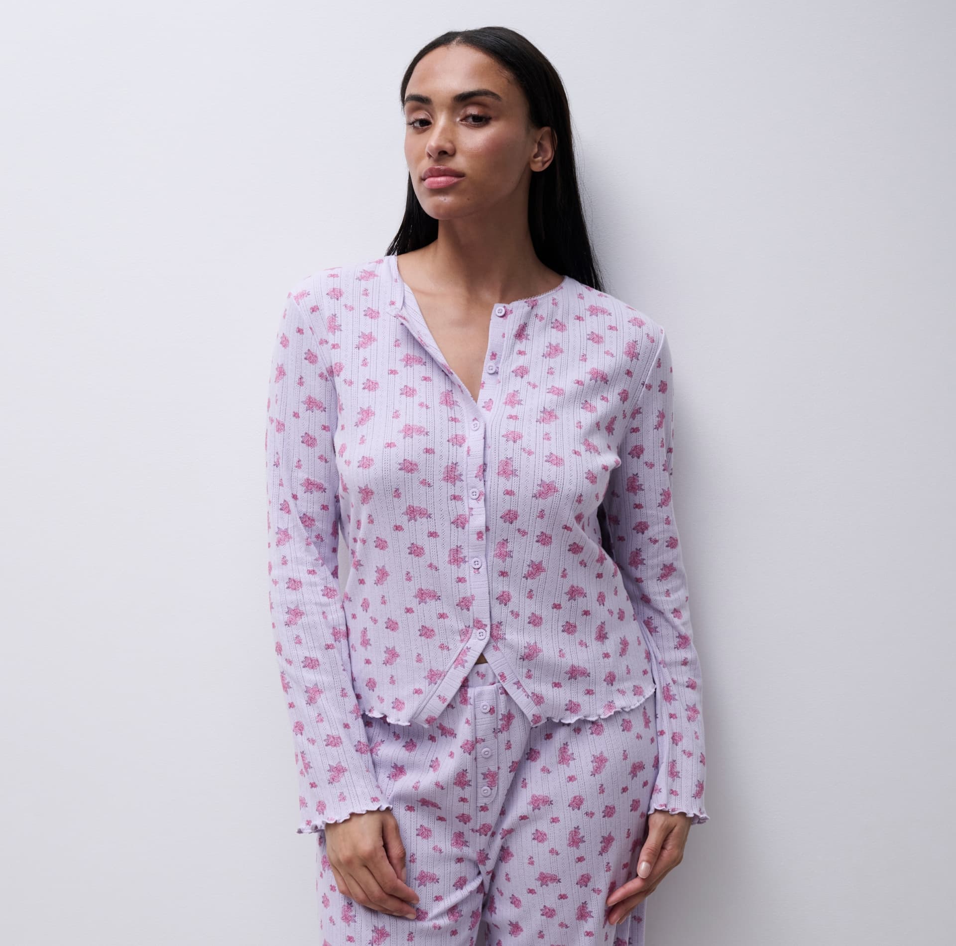 Woman in floral-patterned pajamas with a relaxed pose against a plain white background.