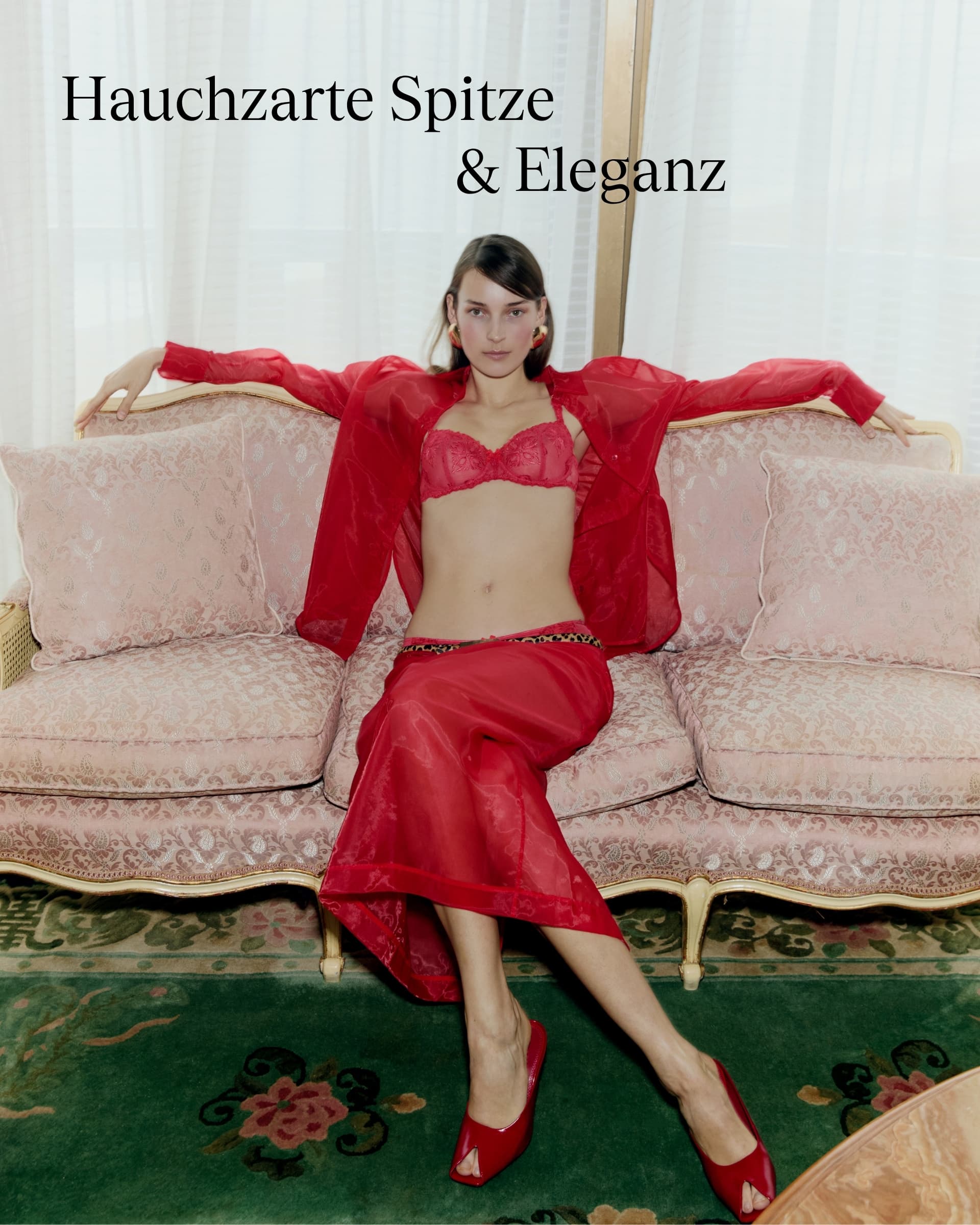 A woman in red lingerie and sheer robe lounges on an ornate sofa against lacy curtains, with the text "Hauchzarte Spitze & Eleganz."
