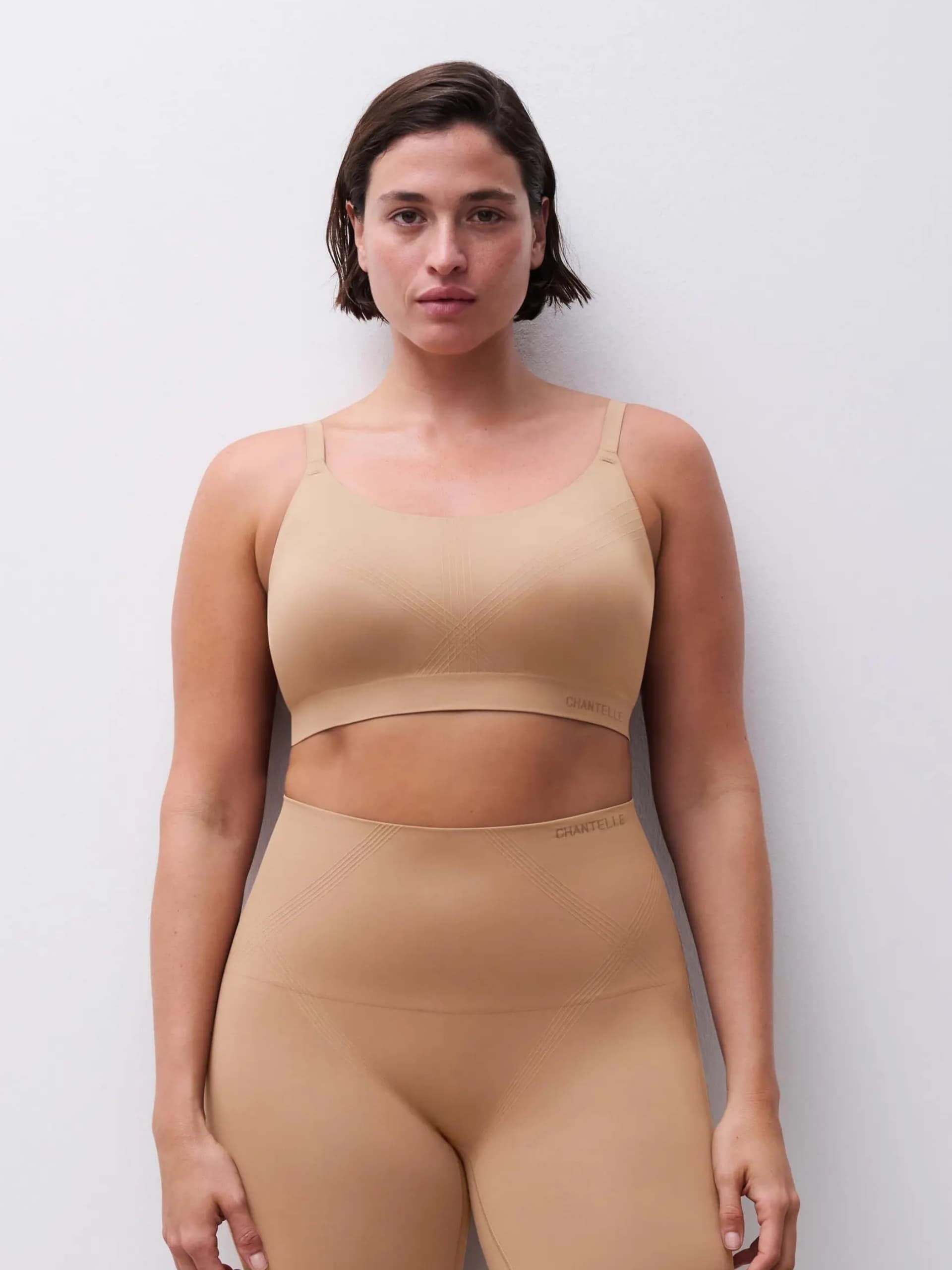 Person wearing shapewear, standing against a plain white wall.