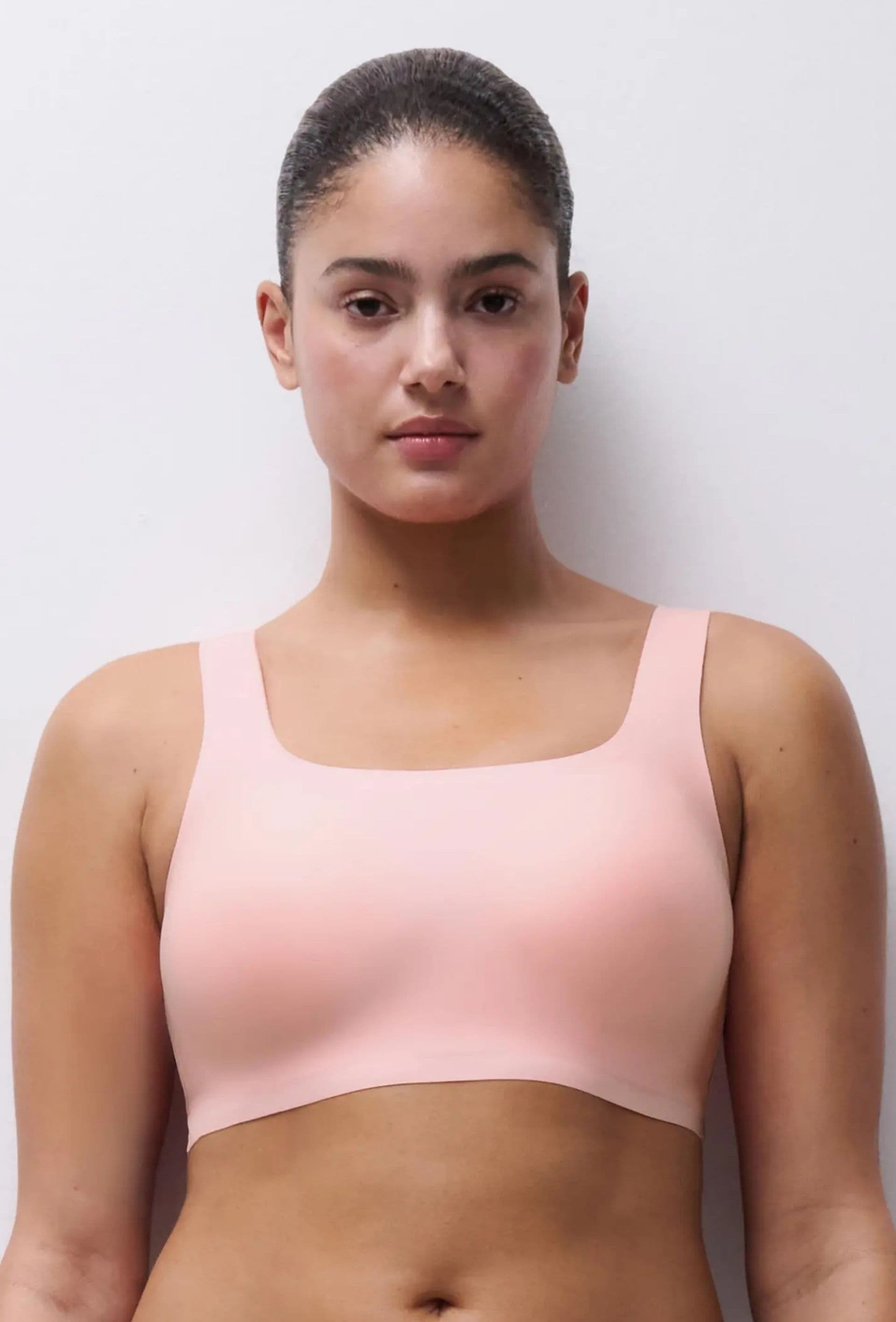 Person wearing a light pink, seamless sports bra against a plain background.