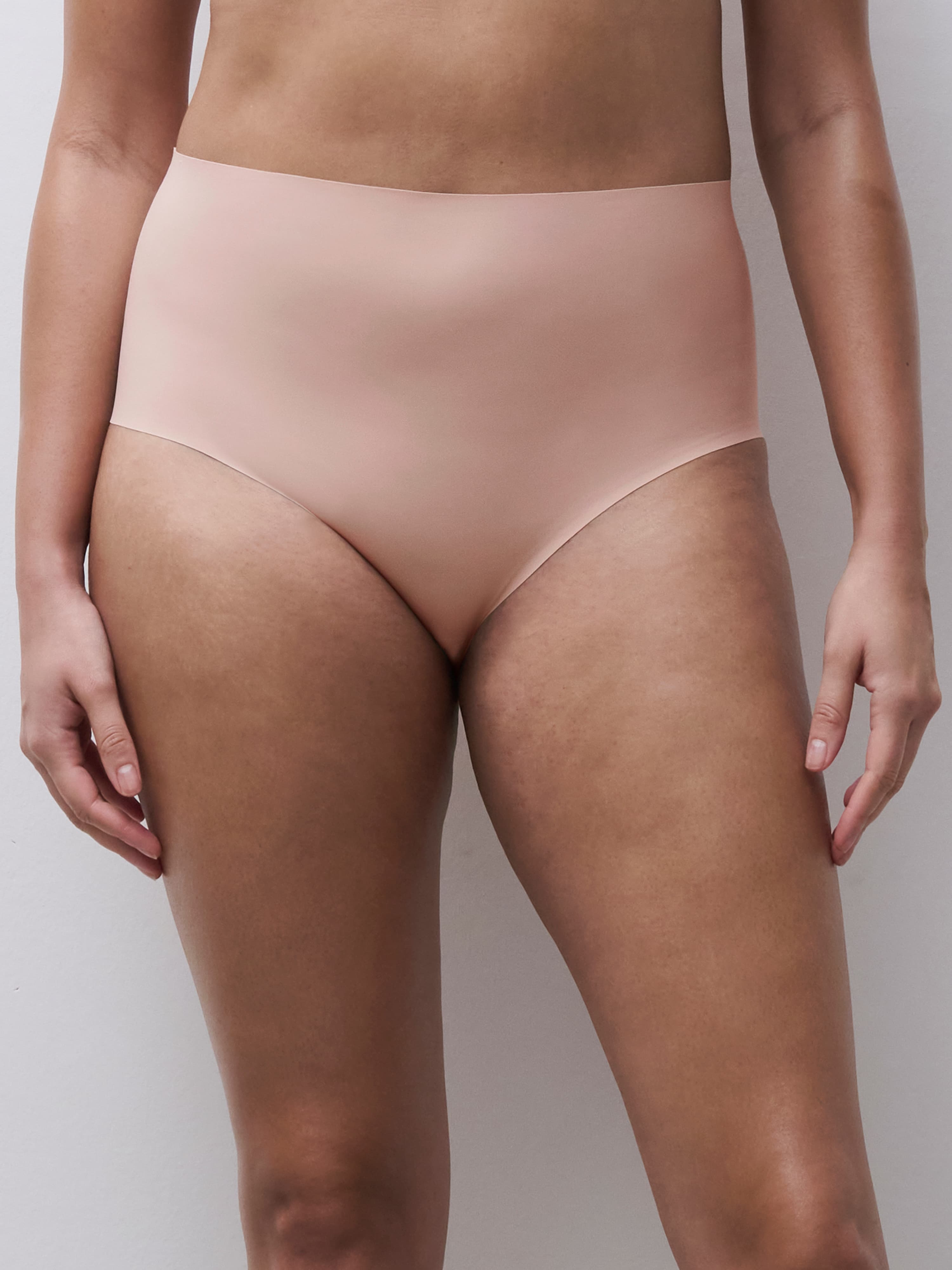 Person wearing high-waisted, seamless soft pink underwear against a plain background.