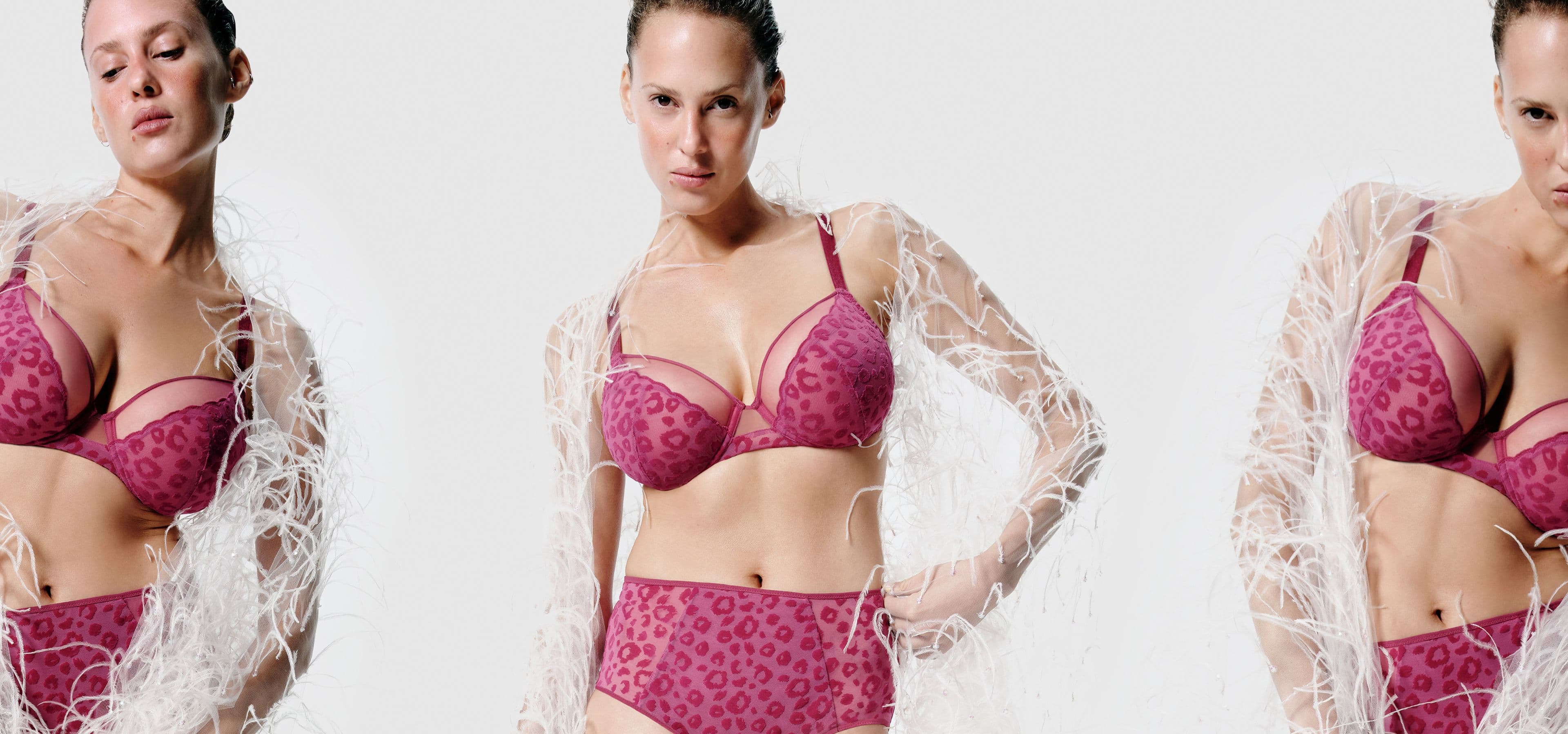 Three women in pink leopard print lingerie and white feathered shawls pose confidently against a plain background.