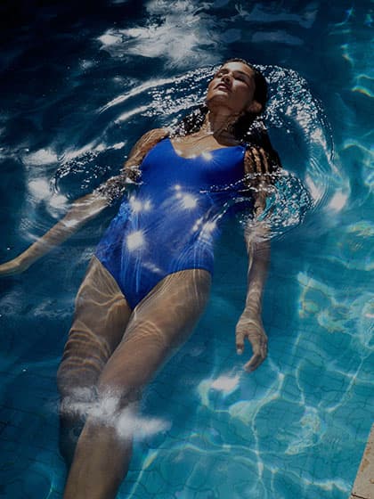 Blauer Badeanzug am Model, die im Wasser liegend schwimmt