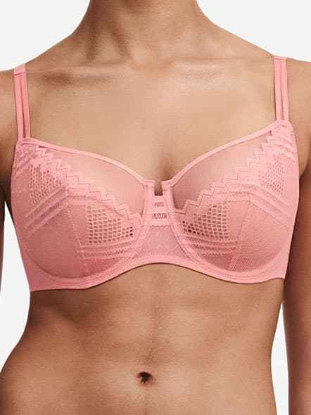 A person wearing a pink lace bra with decorative patterns and adjustable straps, shown from the shoulders to the waist.