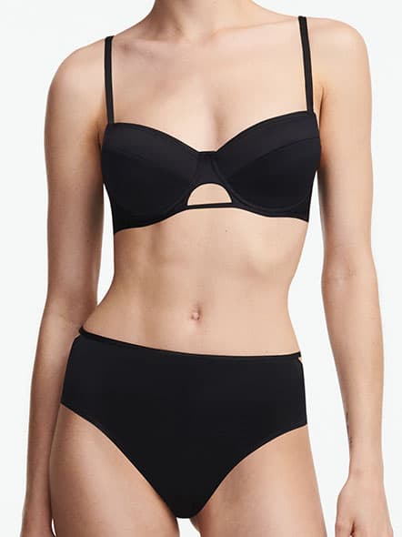 Person wearing a black bikini with high-waisted bottoms and a cut-out detail on the top, standing against a plain white background.