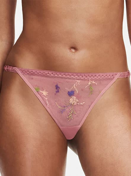 A person wearing pink embroidered floral mesh underwear, showcasing a delicate and intricate design.