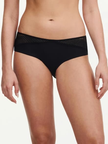 Woman wearing black bottoms with mesh detail on hips, shown from the waist down.