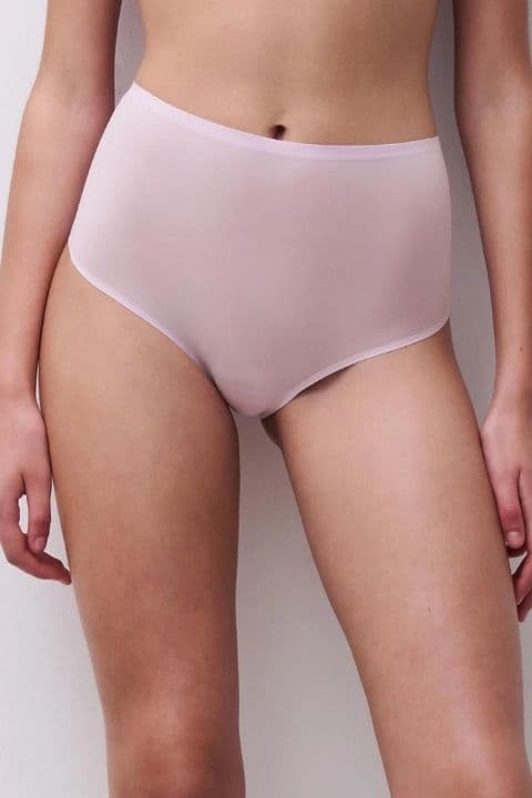 Person wearing high-waisted, light pink underwear against a plain background.