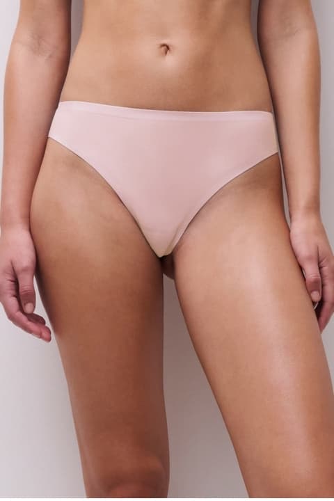 Person wearing pastel pink underwear, shown from mid-torso to thigh against a neutral background.