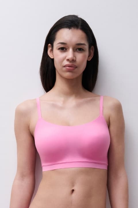 Woman wearing a pink seamless sports bra, standing against a plain, light-colored background.
