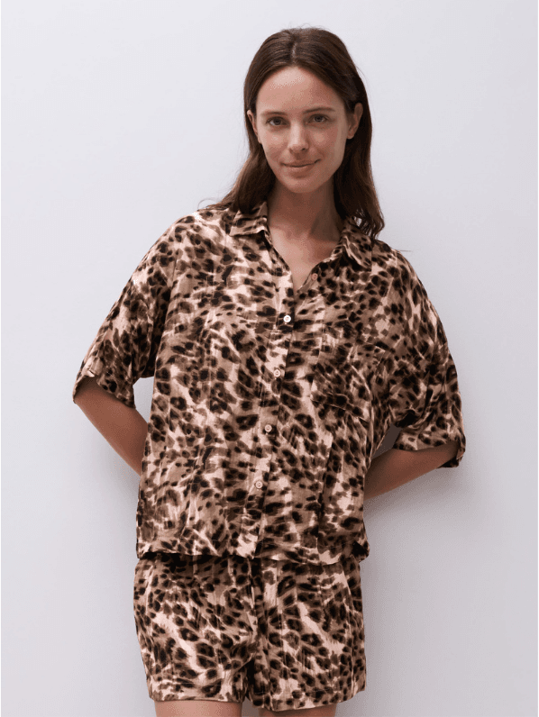 Person wearing a matching leopard print shirt and shorts set, standing against a plain white background.