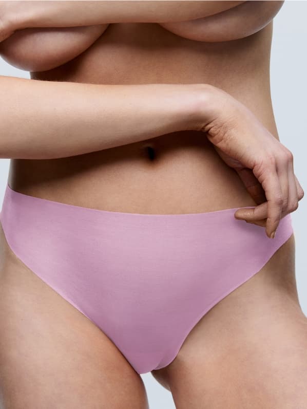 A person soft pink seamles bottoms, standing against a plain white background.