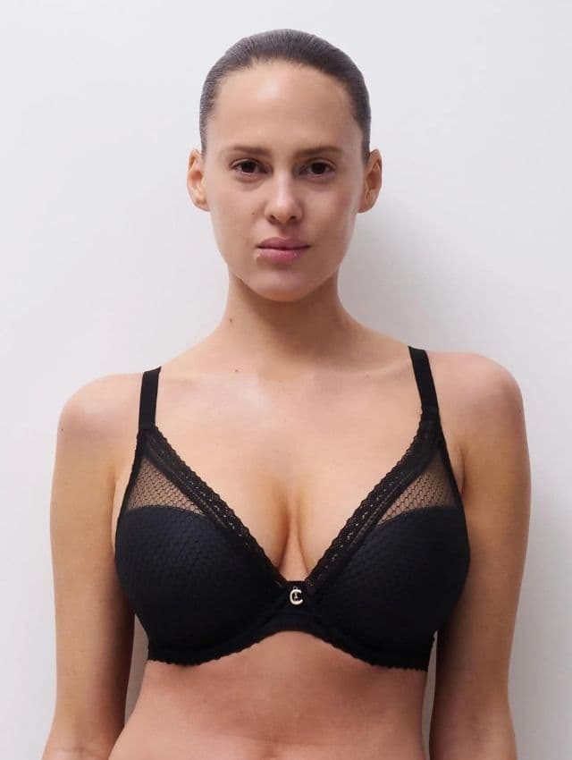 Person wearing a black lace bra with a white background.