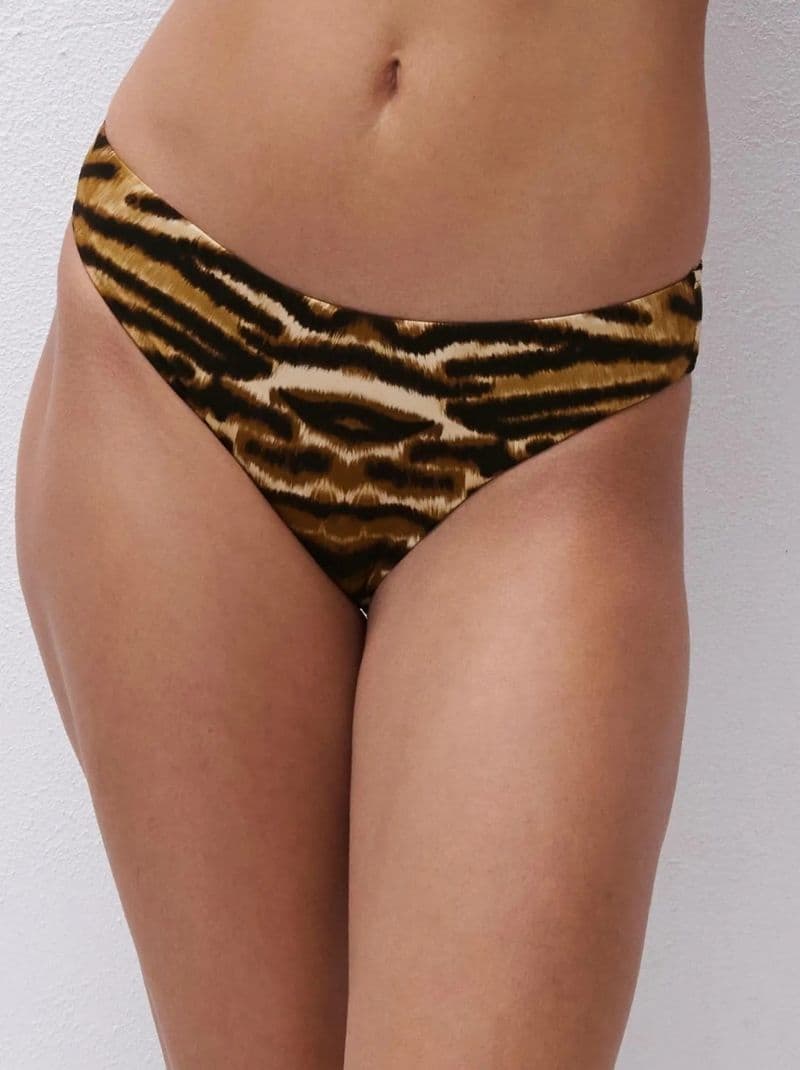 Close-up of a woman wearing a tiger-print high-cut bikini bottom against a light background.