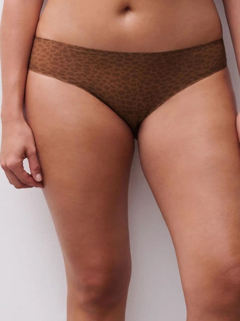 Person wearing brown leopard-print underwear standing against a white wall.