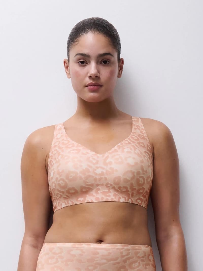 Person wearing a peach leopard-print bra and high-waisted bottoms, standing against a plain white background.