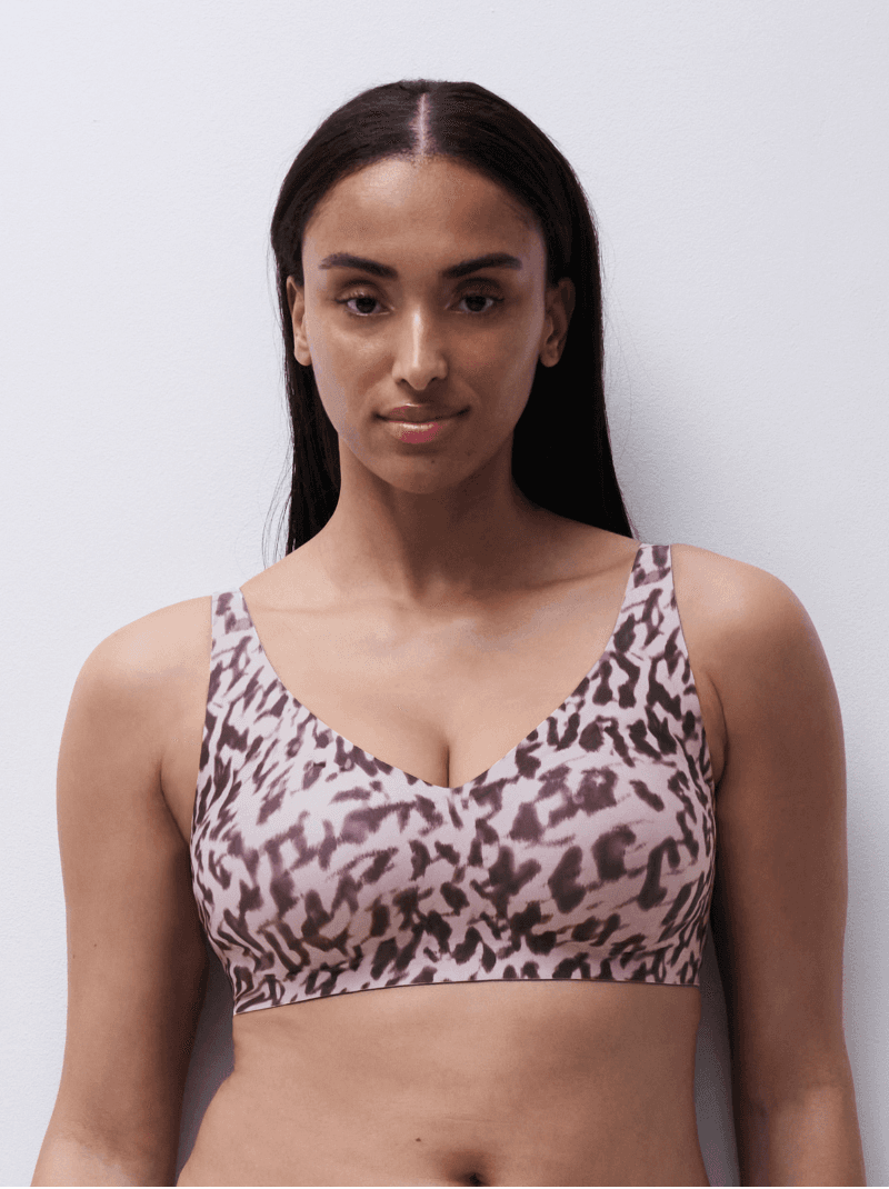 Woman in a patterned sports bra poses against a white background.
