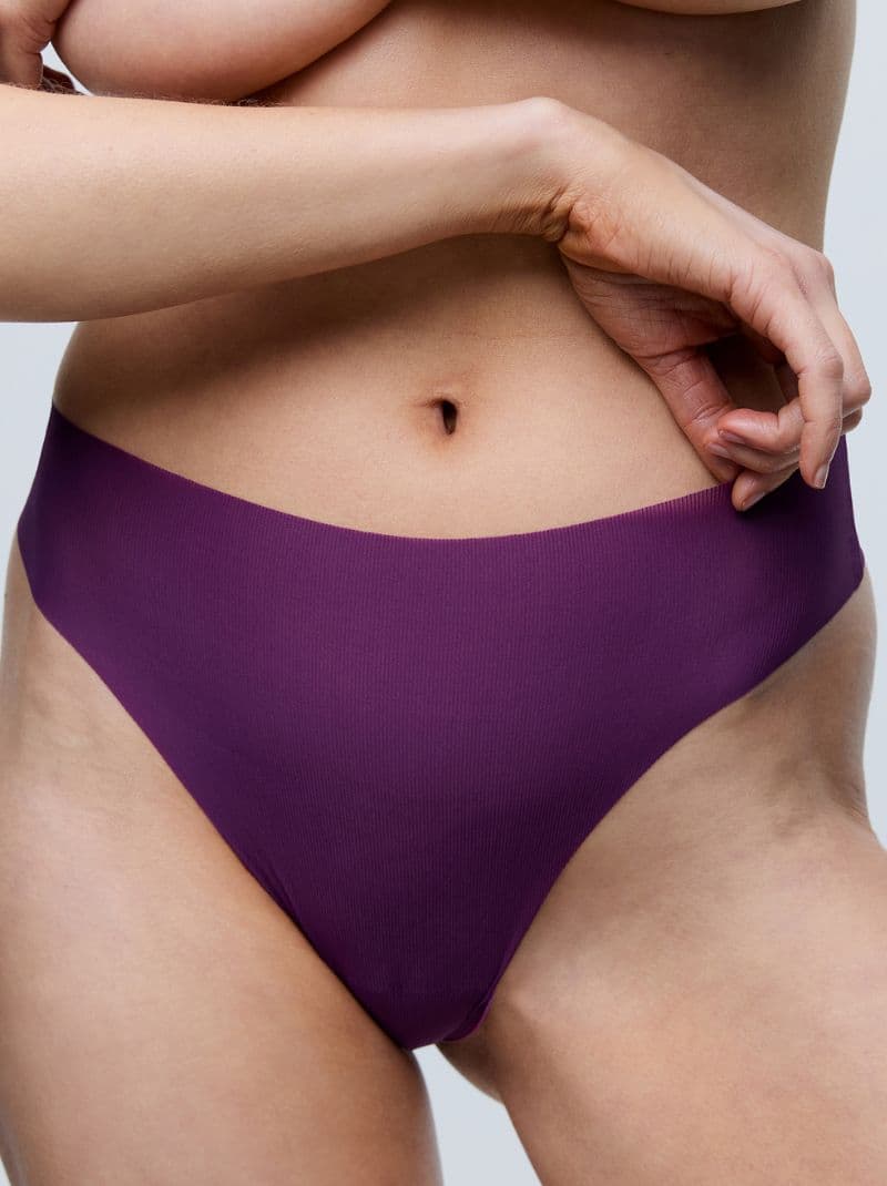A person wearing deep purple seamless underwear, showing a close-up of their midsection against a neutral background.