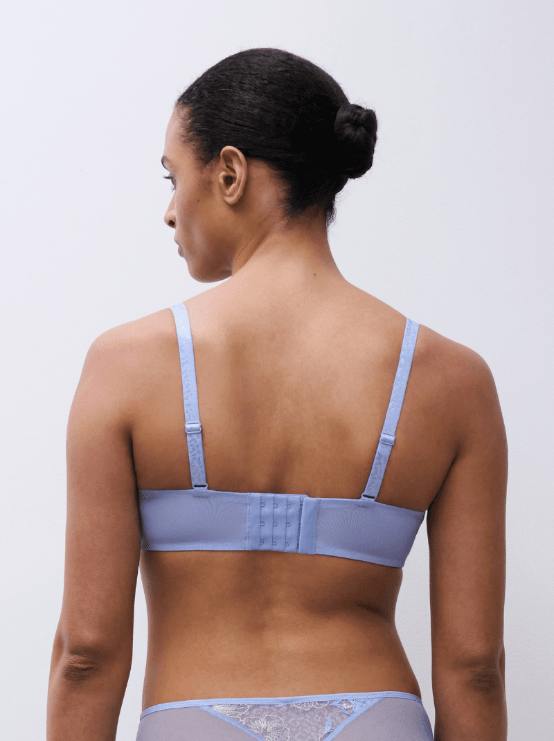 A person with tied-back hair is wearing a light blue bra, viewed from behind, against a plain white background.