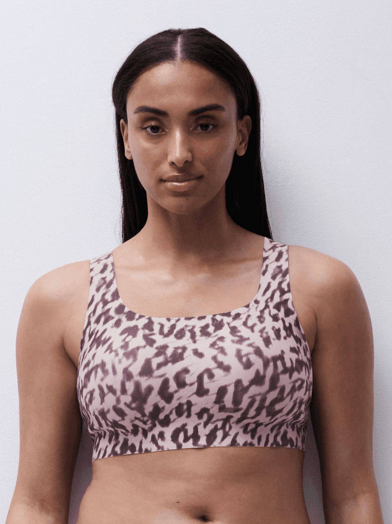 Woman wearing a leopard-print sports bra, standing against a white background.