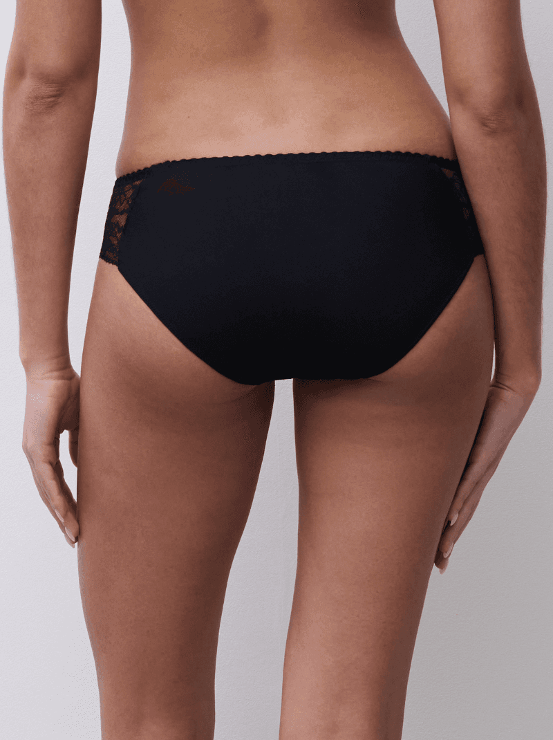 Back view of a person wearing black lace-trimmed underwear, showing the bottom half of the body.
