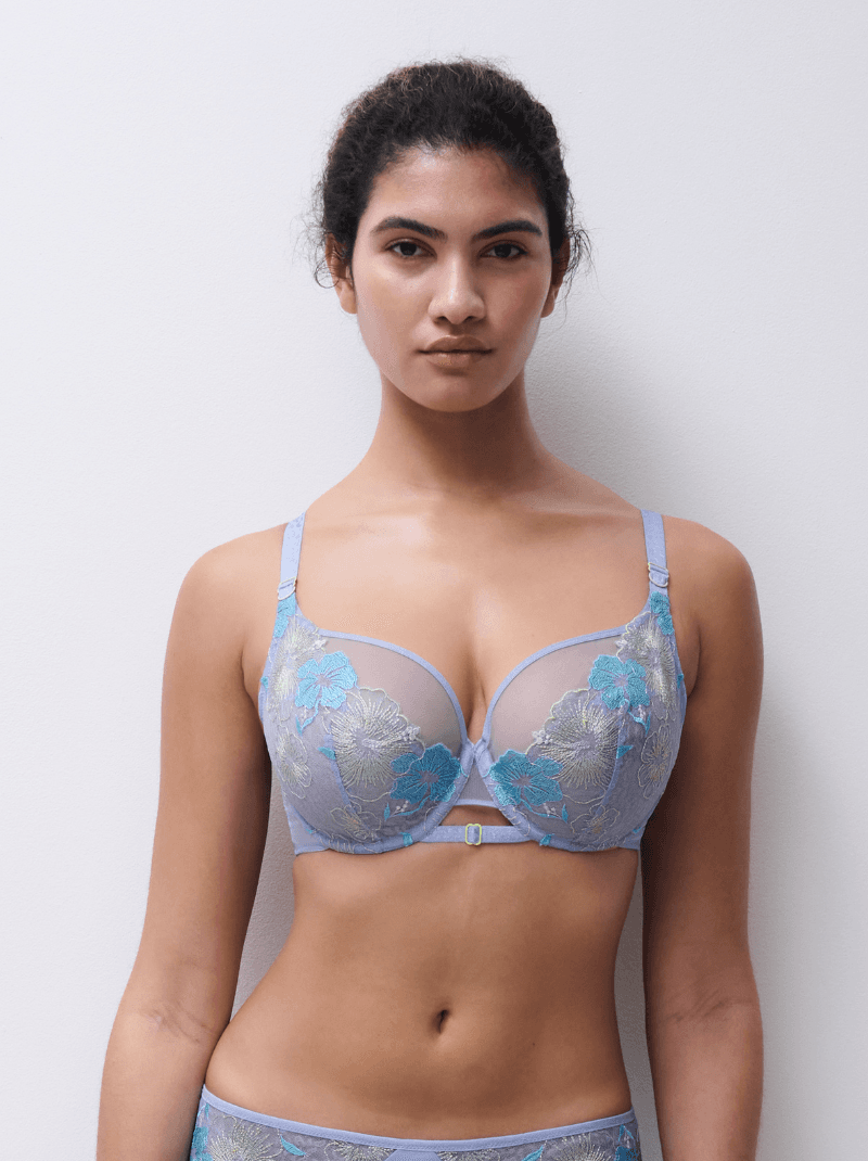 Person wearing a light purple floral lace bra and matching underwear, standing against a white background.