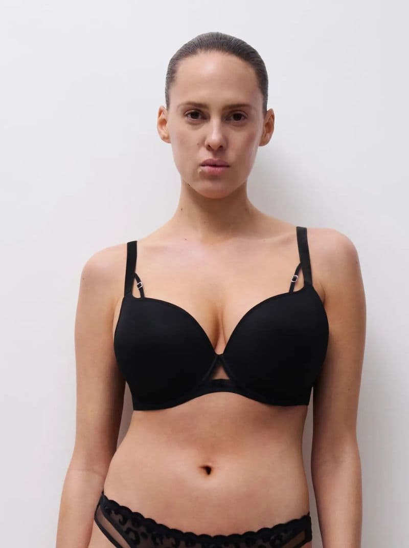 Person wearing a black bra and matching underwear, standing against a plain white background.