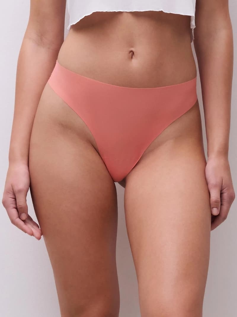 Model in guave seamless underwear and a cropped white top, standing against a neutral background.