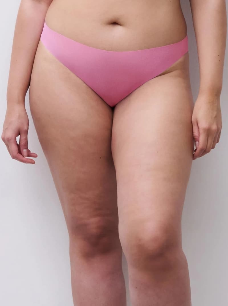 Person wearing pink bottom, showing a close-up of the stomach and thighs against a plain background.
