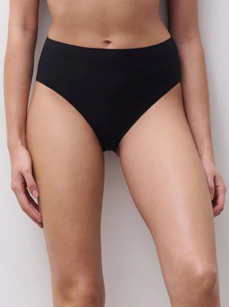 Person wearing high-waisted black underwear, showing the midsection and thighs against a neutral background.