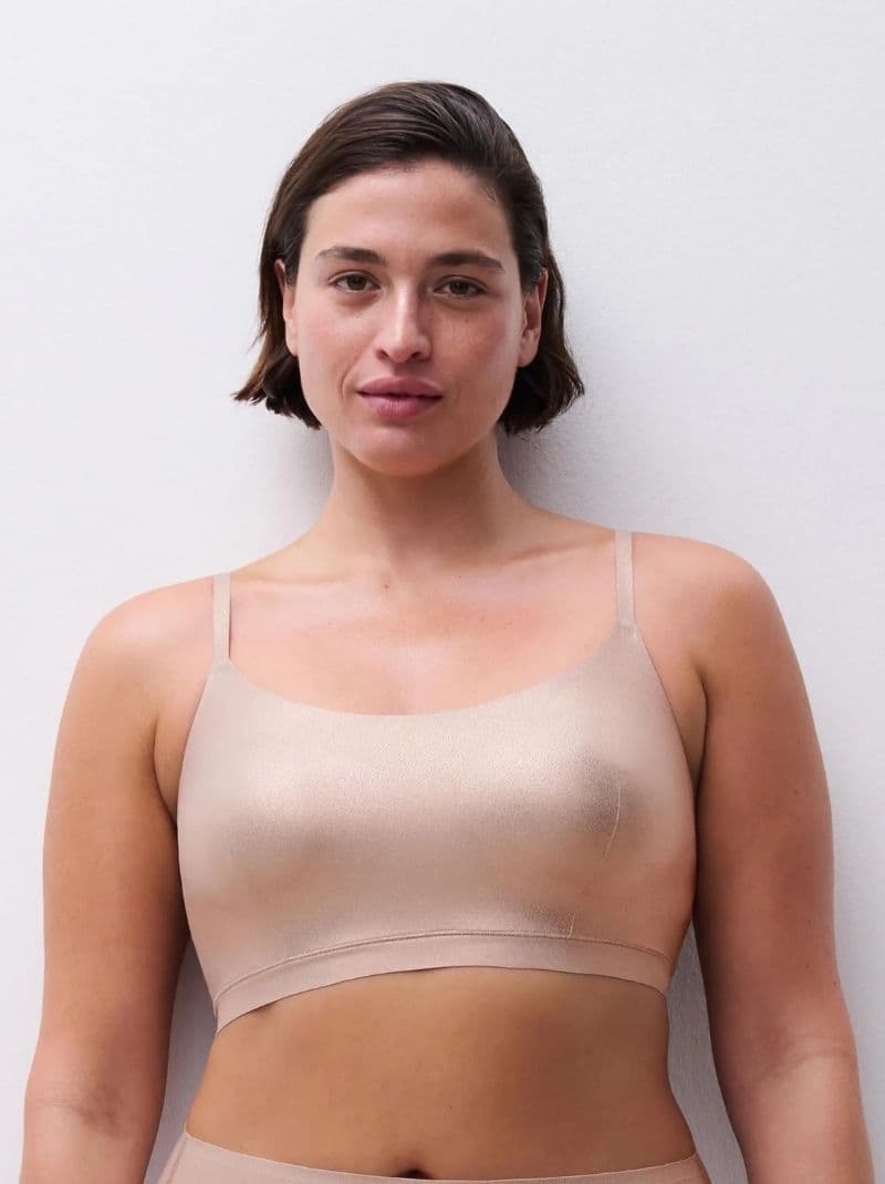A person wearing a golden glow colored seamless bra, standing against a plain white background.