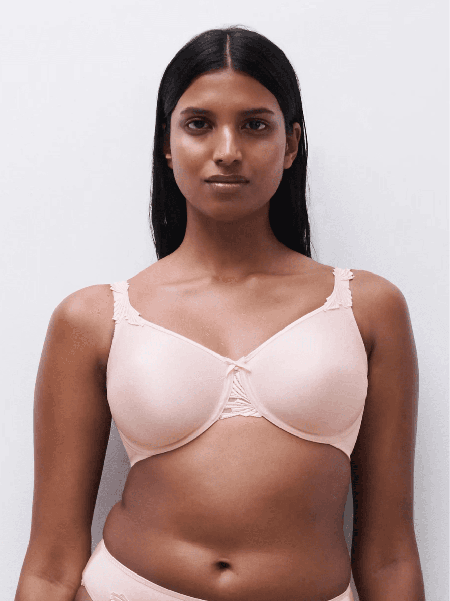 Person wearing a light bra with lace details, standing against a plain background.