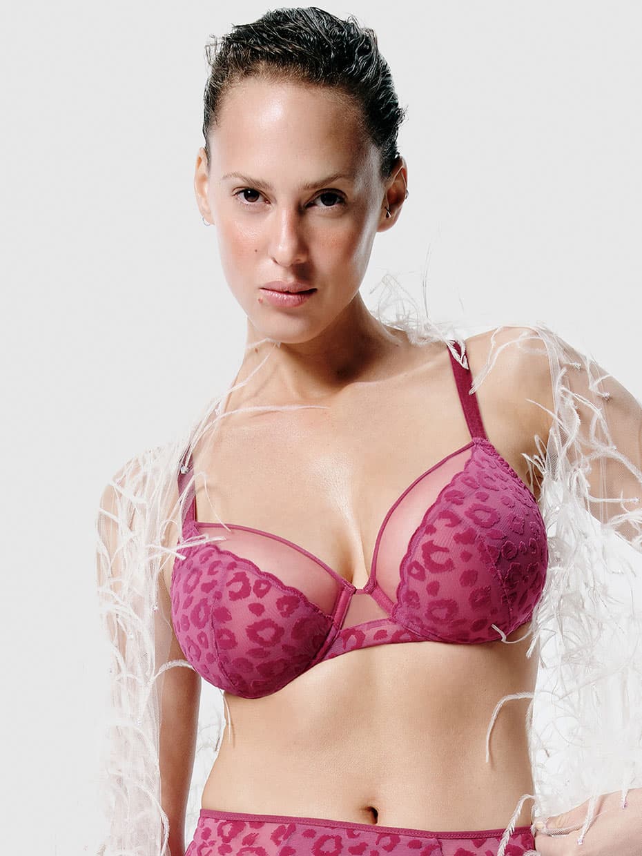 Person wearing a pink leopard-print bra and matching bottoms, with a white feathered accessory draped over their shoulders.