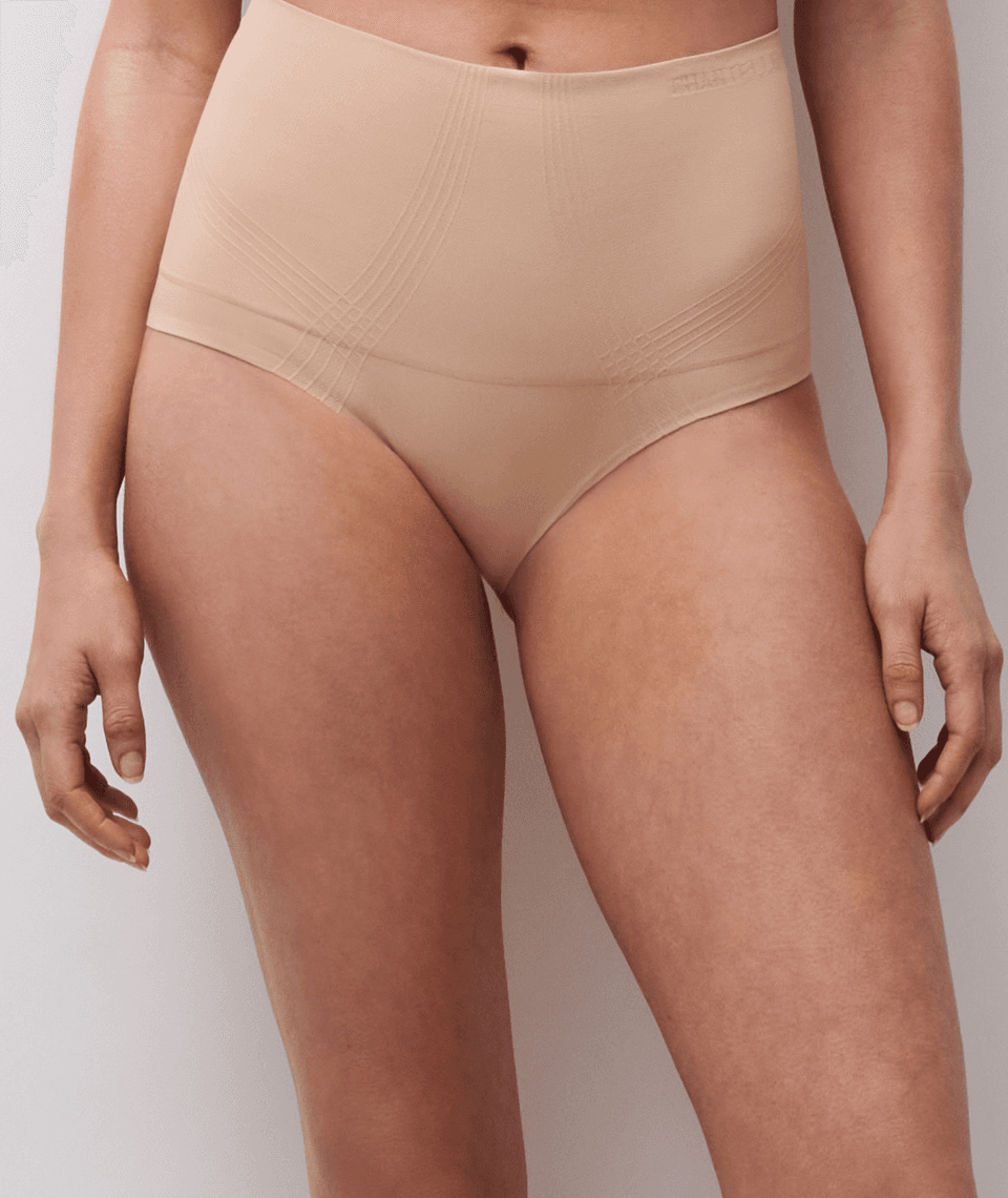 A person wearing high-waisted, seamless beige underwear, shown from the waist to mid-thigh, against a plain background.