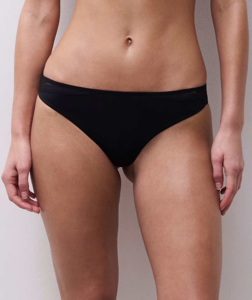 Person wearing black underwear, facing forward against a neutral background.