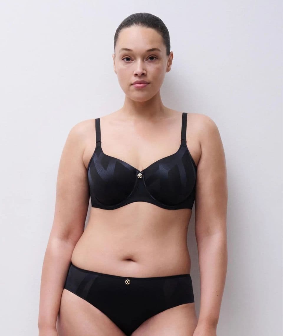 Person wearing a matching black bra and underwear set, standing against a plain white background.