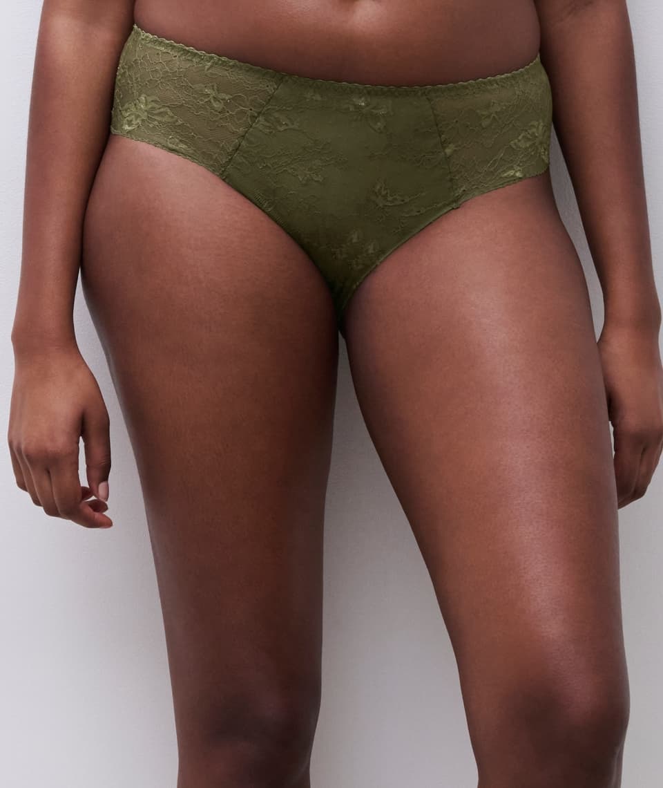 Person wearing olive green lace-patterned high-waisted underwear, standing against a plain white background.