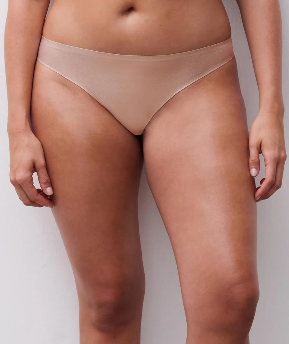 Close-up of a person wearing light colored seamless underwear against a light background, focusing on the lower torso and thighs.