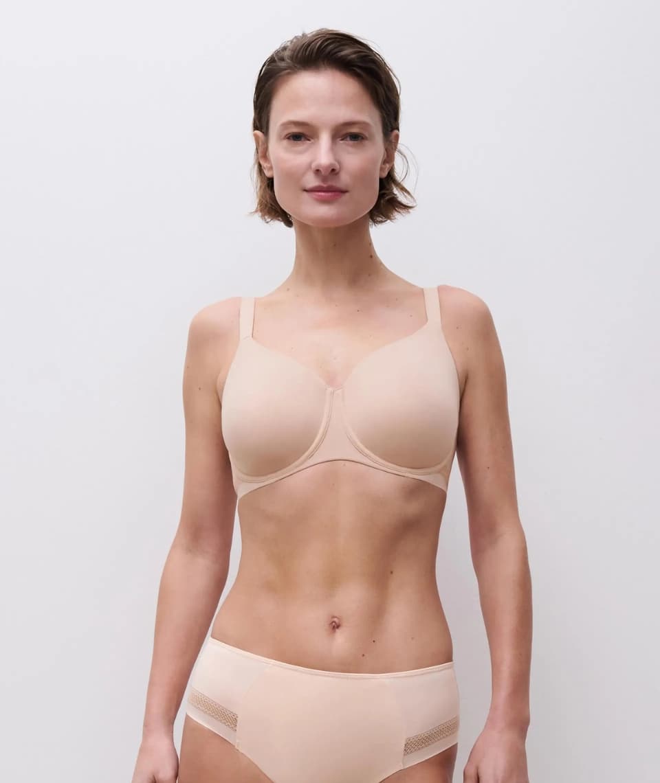 Person wearing a beige bra and underwear set against a plain white background.