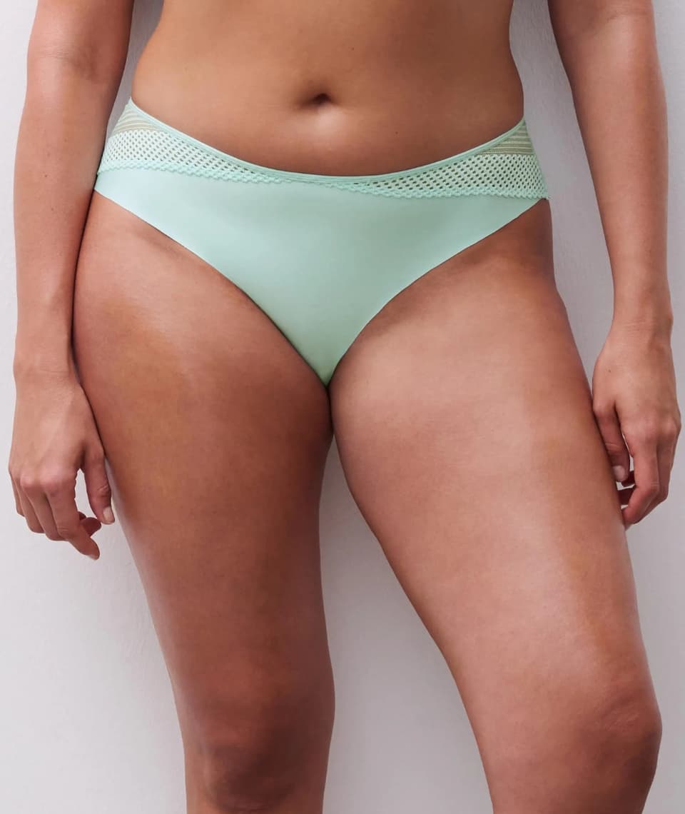 Person wearing light green underwear with lace detailing at the waistband, standing against a neutral background.