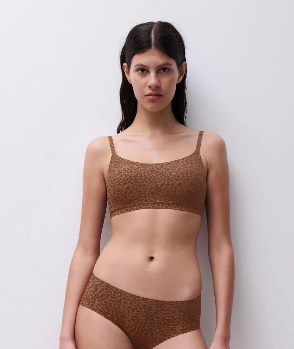 Person wearing a matching brown leopard print bralette and panties, standing against a plain white background.