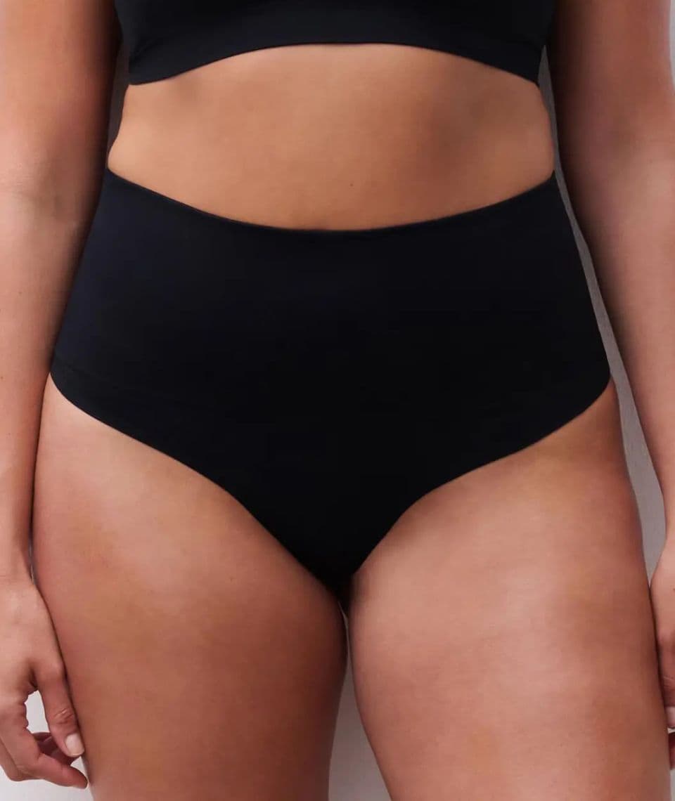 Person wearing high-waisted black underwear, showcasing a smooth, seamless design. Upper body partially visible.