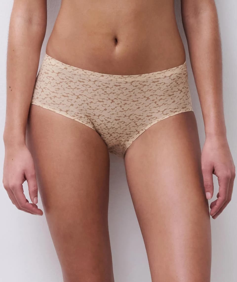 Person wearing beige patterned underwear, showing torso and upper legs, standing against a plain background.