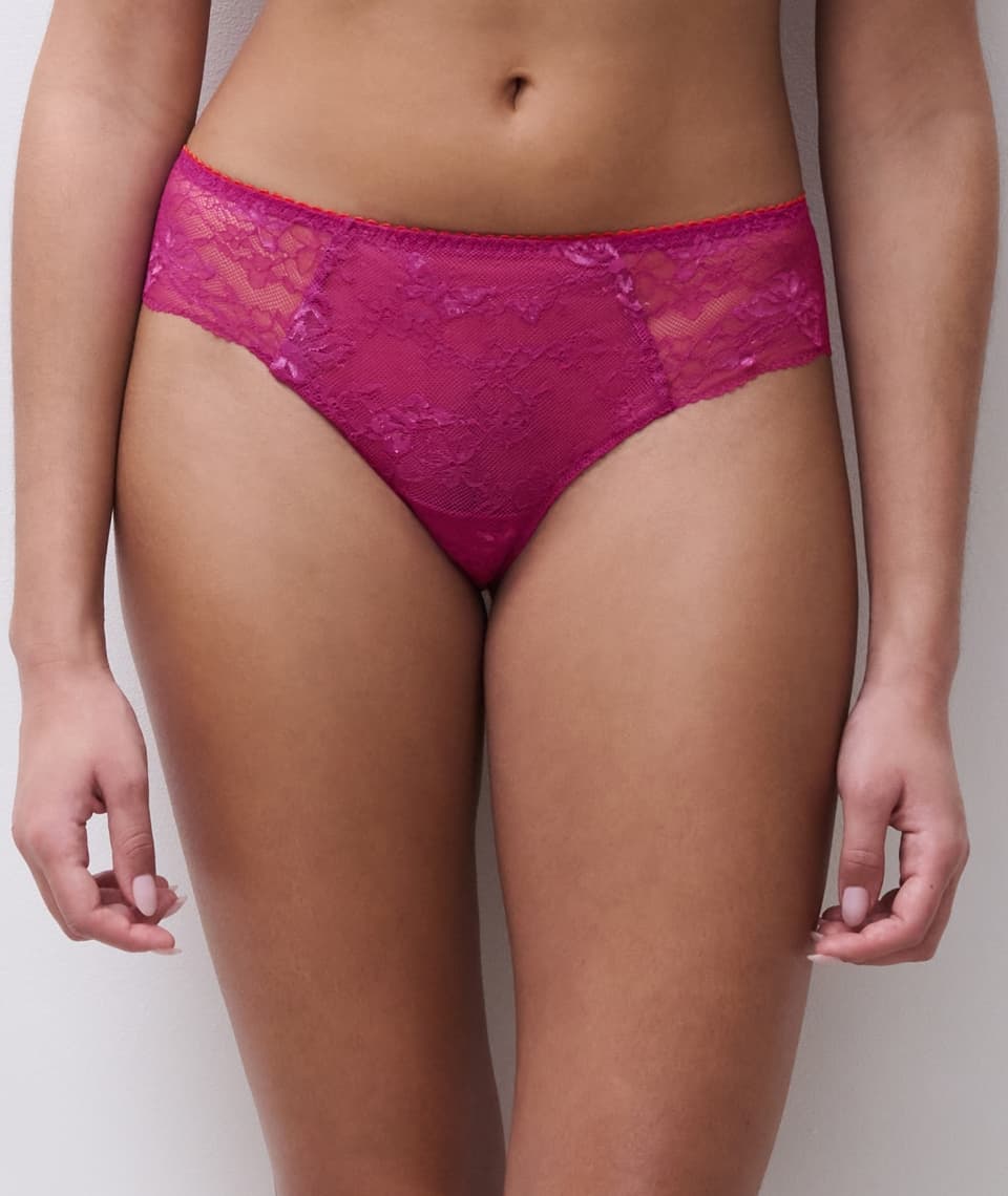 Person wearing pink lace underwear, standing against a plain background.