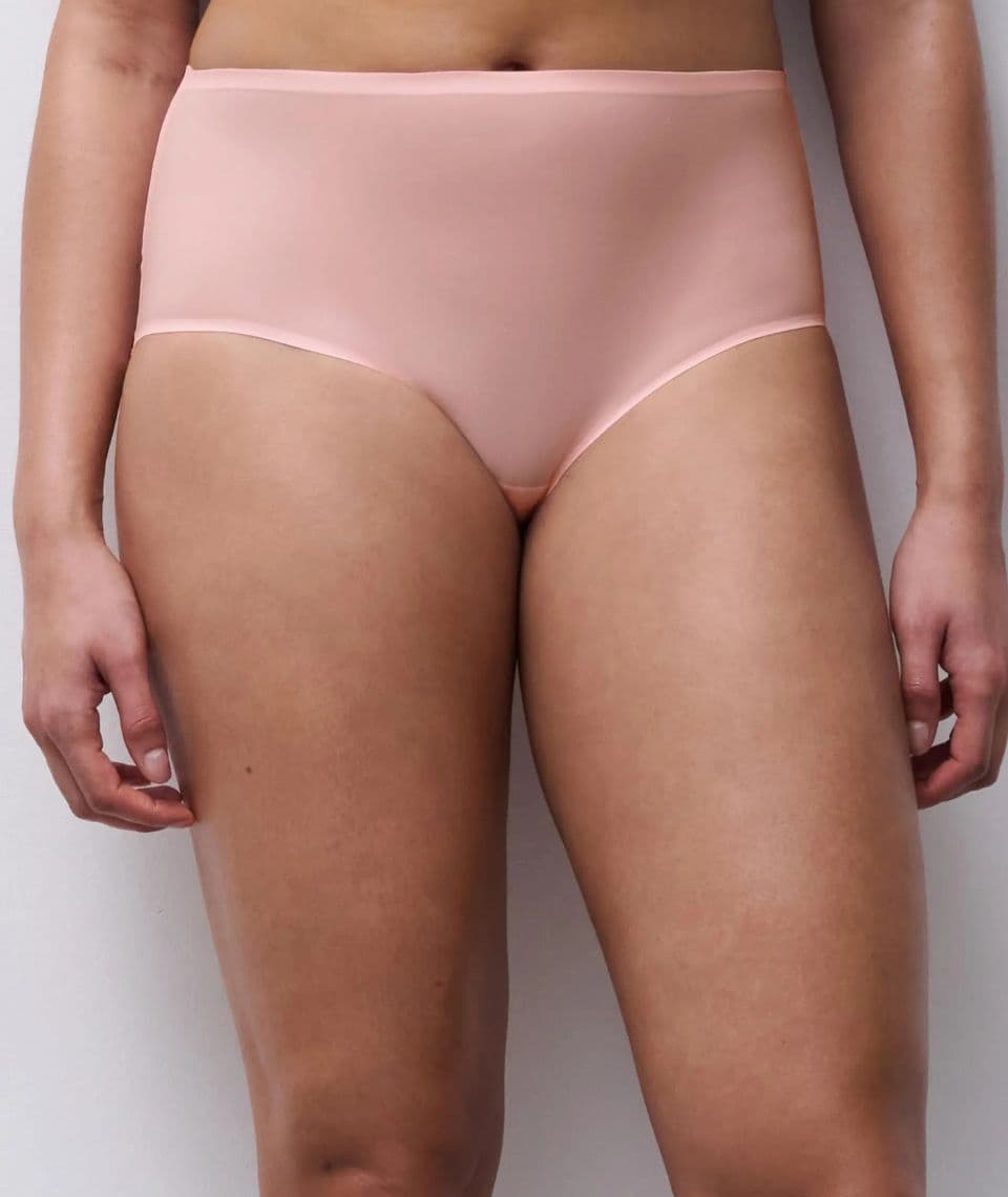 Person wearing high-waisted, pink-colored underwear, standing against a neutral background.