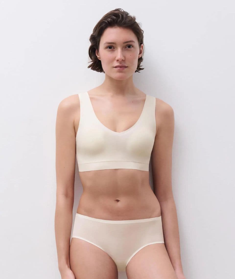 Person wearing a white colored seamless bra and panties, standing against a plain white background, looking directly at the camera.